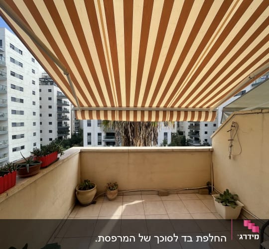 מרפסת עם סוכך מפוספס בצבעים חום ולבן
